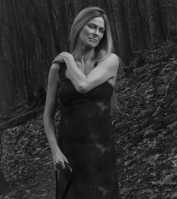 A blackandwhite photograph of a woman in a dress.